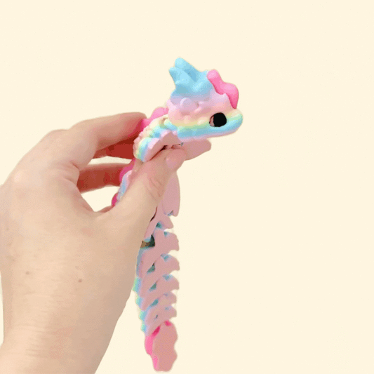 A rainbow-toned fidget dragon toy featuring glittery pink details, with articulated movement for tactile play.
