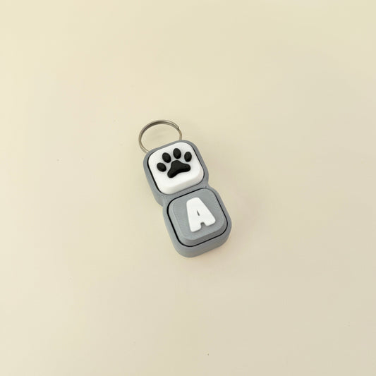 Keychain with paw print and letter 'A' on a beige background