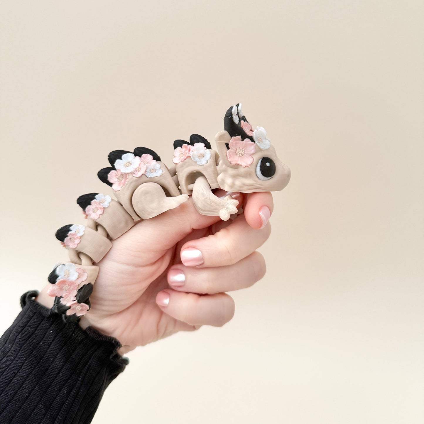 A Floralyn Dragon with a nude body, pink and white flowers, and black horns, featuring black and white eyes, fully articulated and detailed.