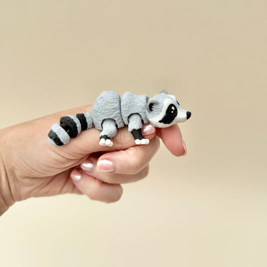 Fidget toy shaped like a raccoon, featuring movable legs, tail, and head for sensory play.