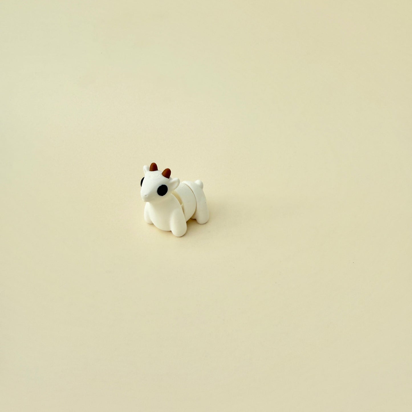 White goat fidget toy with brown horns and black eyes, ideal for desk or pocket use.