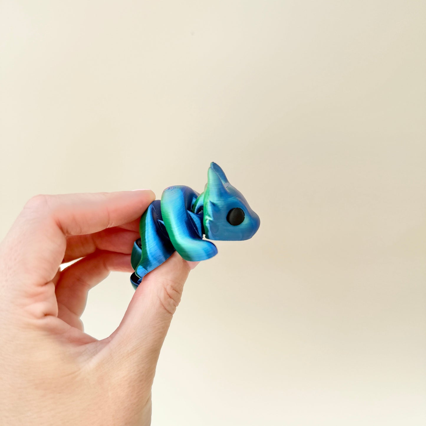 Small articulated dragon fidget toy with shifting colour tones.