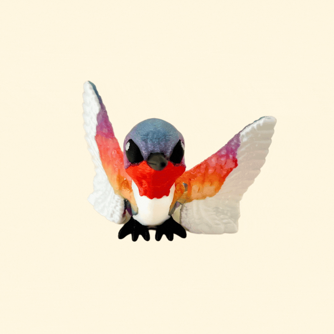 A rainbow-coloured hummingbird fidget toy with articulated wings and a sleek black beak.