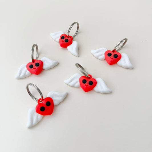 A playful heart keyring featuring fluttering white wings and a cheerful design.