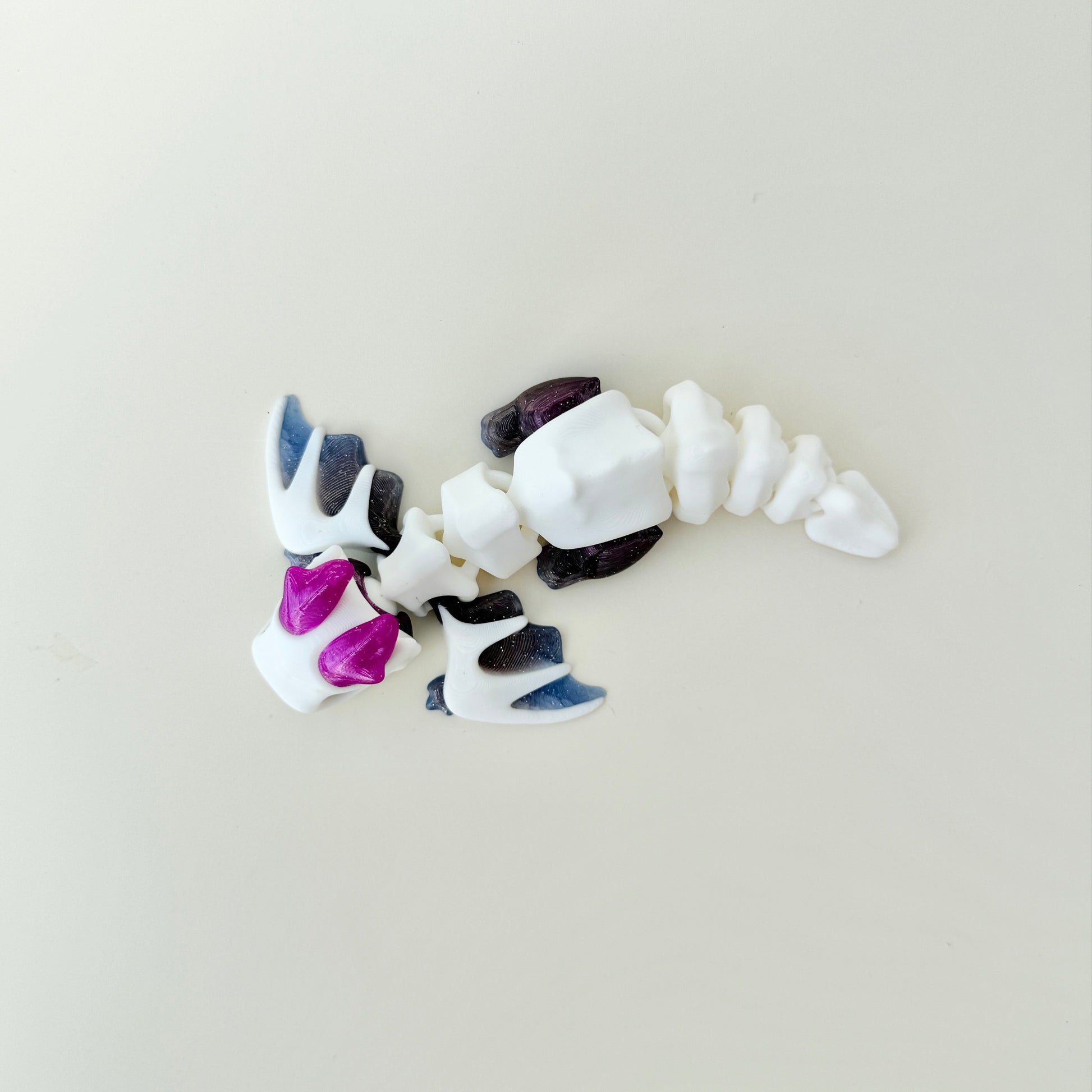 Textured dragon fidget with flapping wings and flexible tail; provides visual sparkle and calming, repeatable motion.