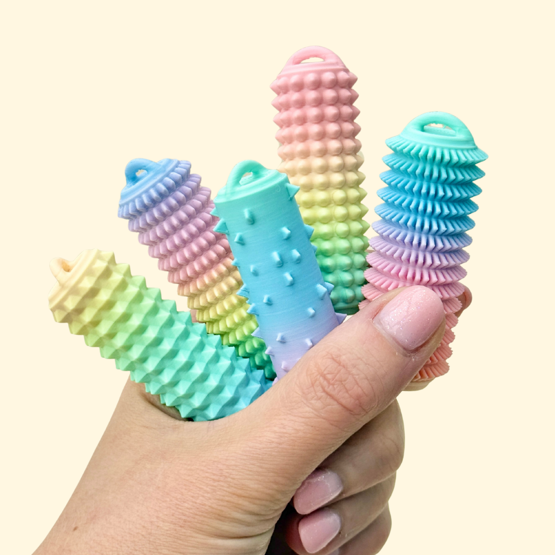 A rigid sensory stim tool designed for palm use with raised texture and included wrist strap.
