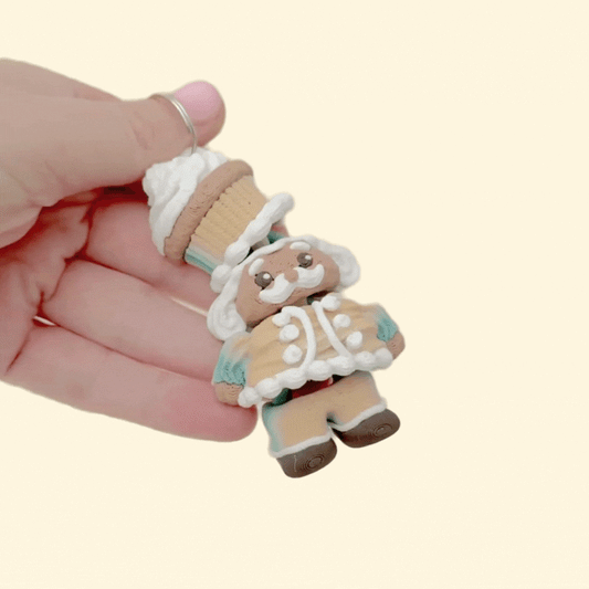 A miniature holiday nutcracker charm with textured surfaces designed for sensory engagement and decoration.