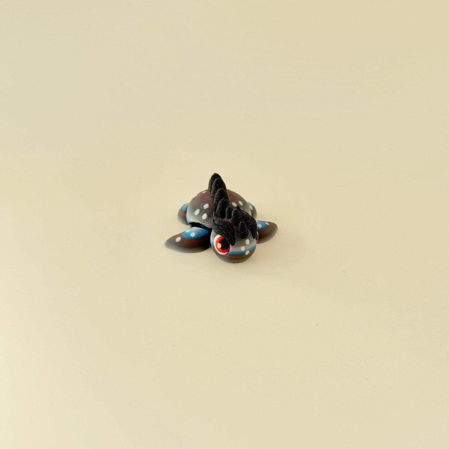 A tactile fidget toy featuring gradient colours in grey, white, brown, and blue with a bold, spiked design.