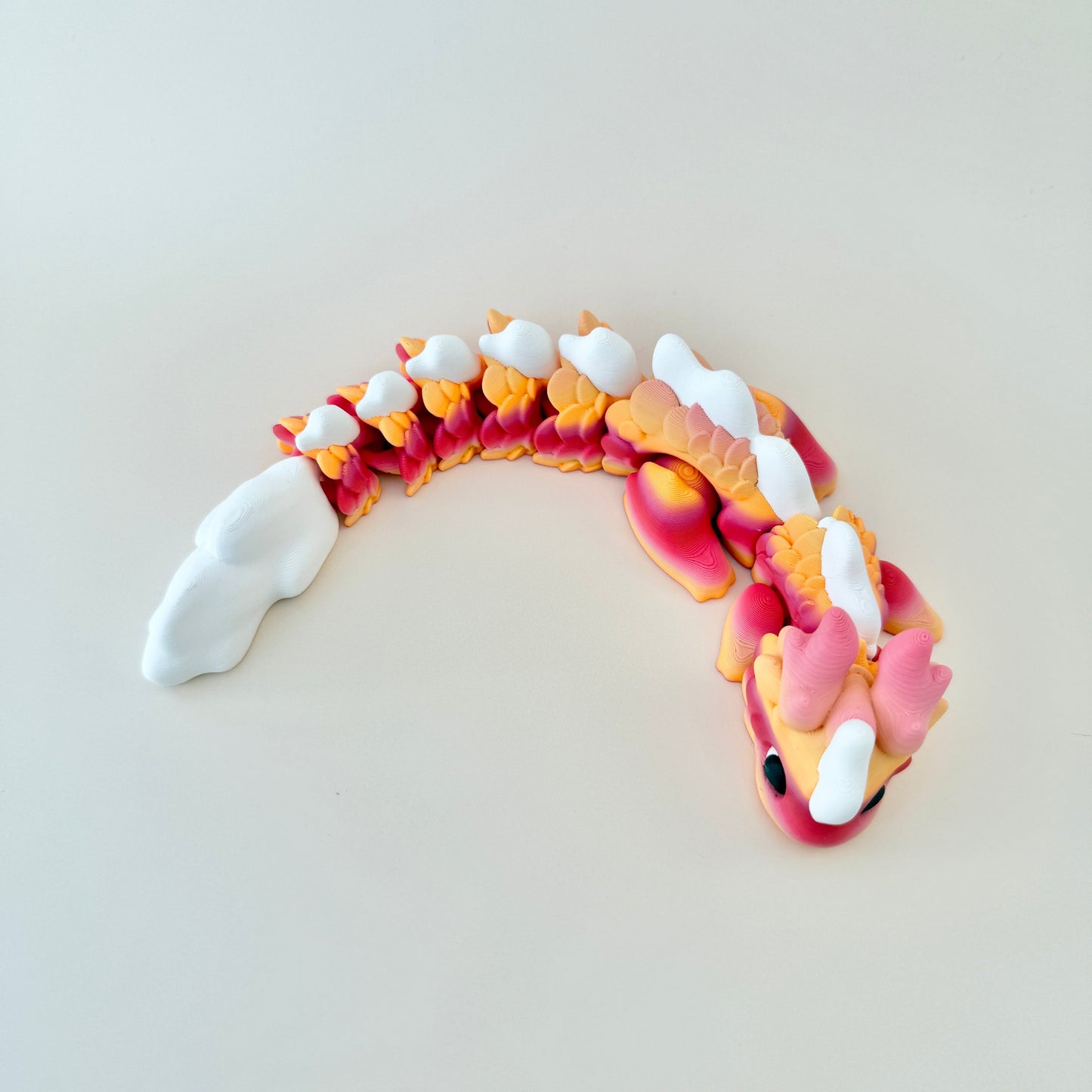 Kaida Scaled Dragon with a white body, peach and pink gradient scales, and smooth, flexible movement.