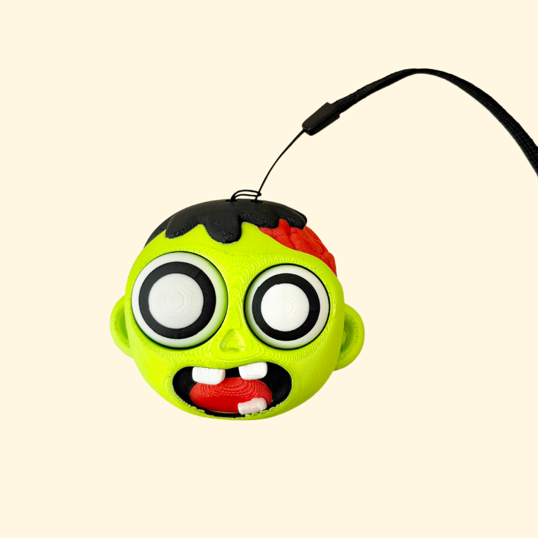 large zombie-themed clicker fidget with two pressable eyes and wrist strap attachment