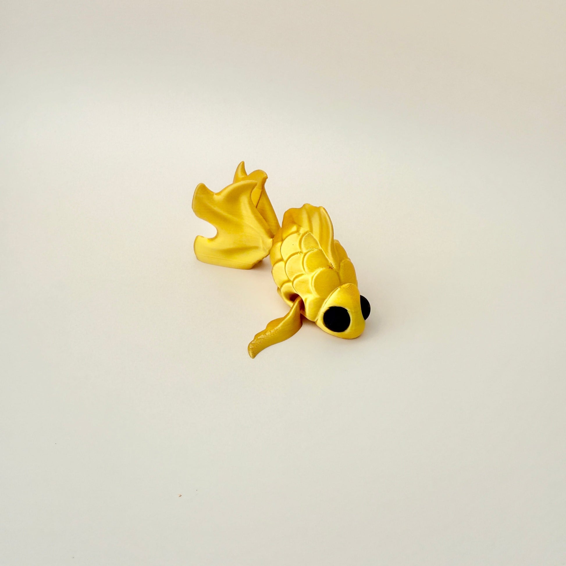 Realistic goldfish fidget toy with movable tail and fins, crafted in shimmering gold filament.