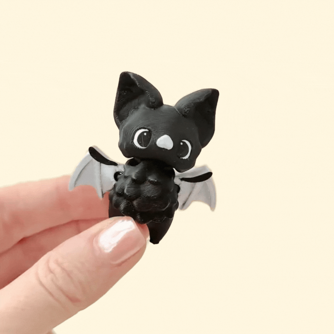 Flexible bat fidget toy with articulated wings and body, black eyes, and smooth detailing.