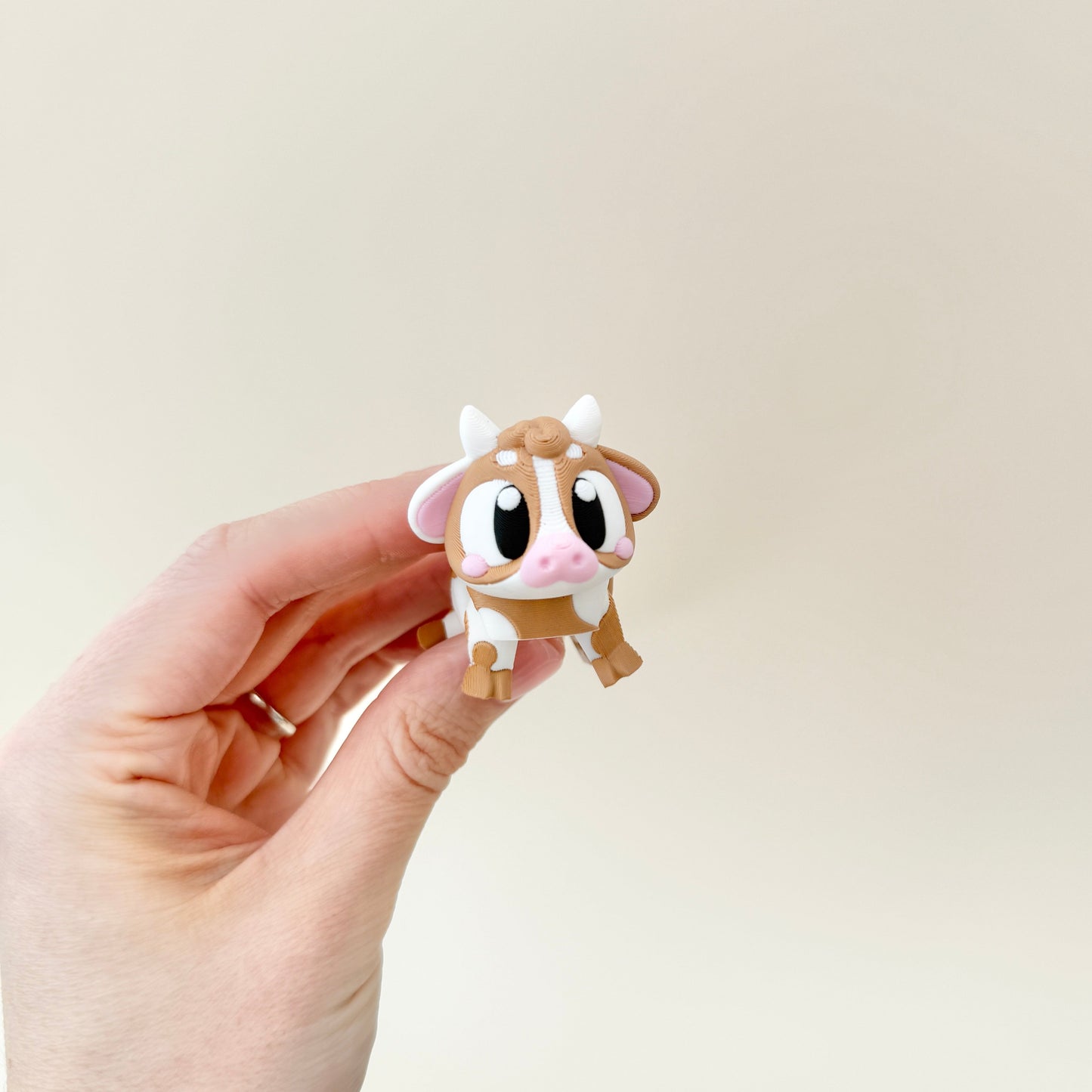 A small, flexible cow fidget toy with a cute farmyard design, ideal for fidgeting.