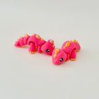 A small dinosaur fidget toy in red with shiny gold accents, designed for standing or lying flat.