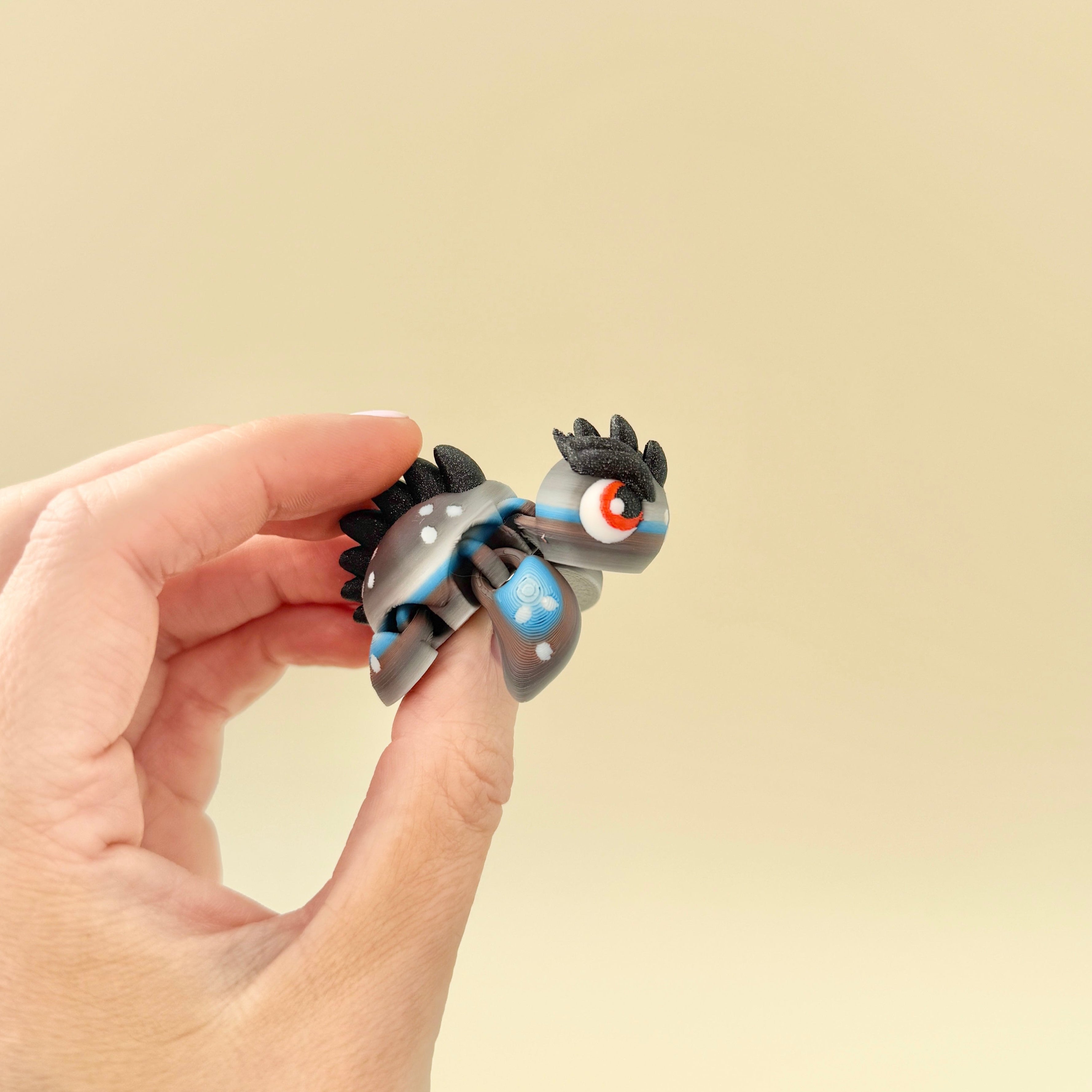 Close-up view showing the red eyes, textured body, and fully articulated limbs of the Dragon Turtle fidget.