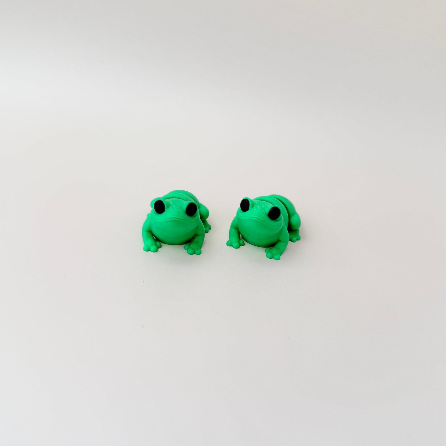 Bright green frog fidget toy featuring black eyes and a fully articulated body for sensory fun.
