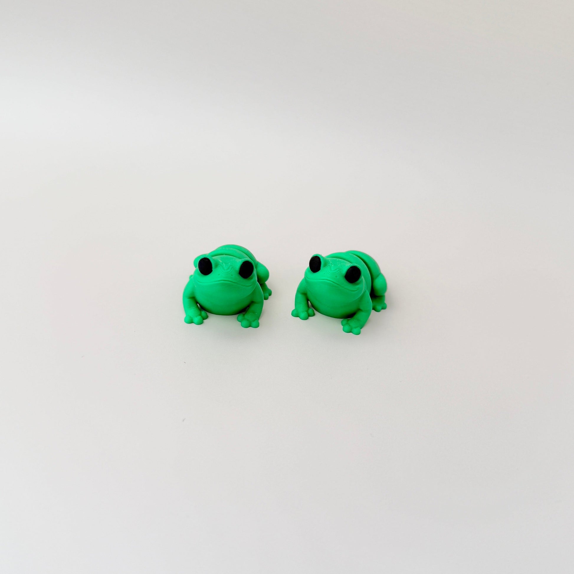 Bright green frog fidget toy featuring black eyes and a fully articulated body for sensory fun.