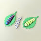 Articulated caterpillar fidget with leaf base for sensory play.
