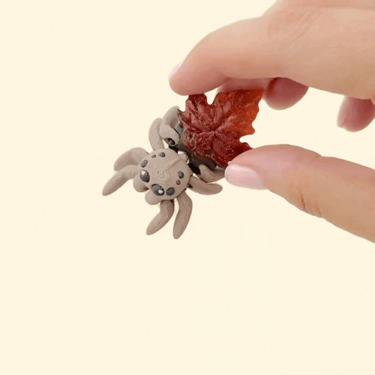 Brown articulated spider with black eyes and an amber gradient leaf shell for quiet fidgeting.
