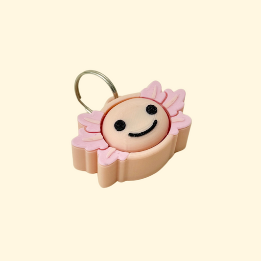Cute sensory clicker with smiley face and head fins, attached to a keyring.