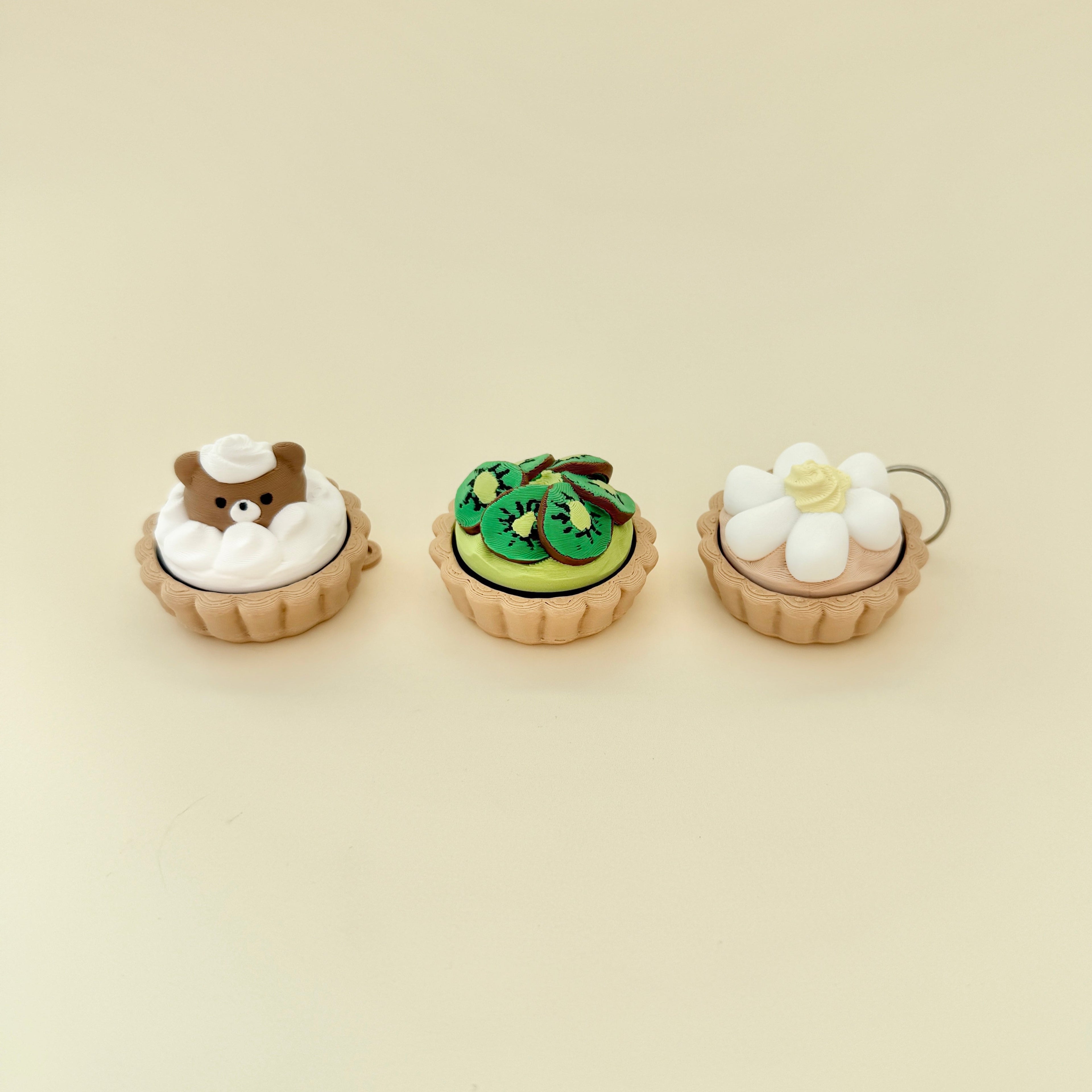 Three fidget clickers shaped like mini tarts, each with a different topping design.