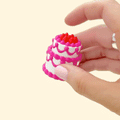 tiered cake-shaped fidget clicker with textured frosting and a press-to-click top
