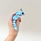 Light blue dragon fidget toy with dark blue accents, silver horns, and a fully flexible body.