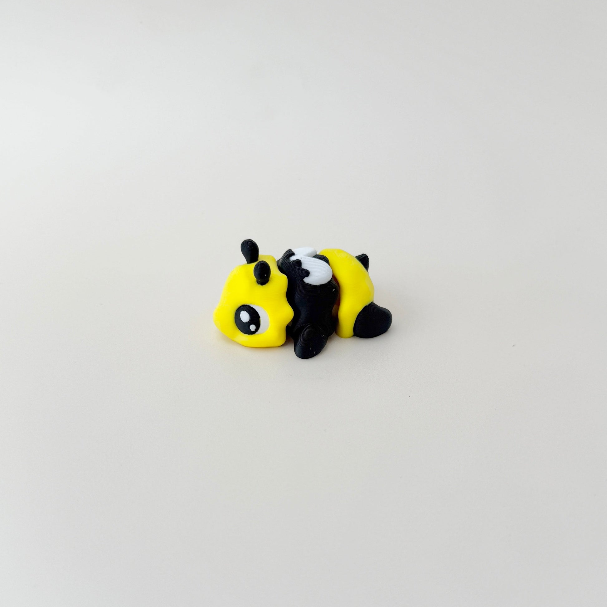 A small, flexible bee fidget toy with a cheerful face and a compact, pocket-friendly design.
