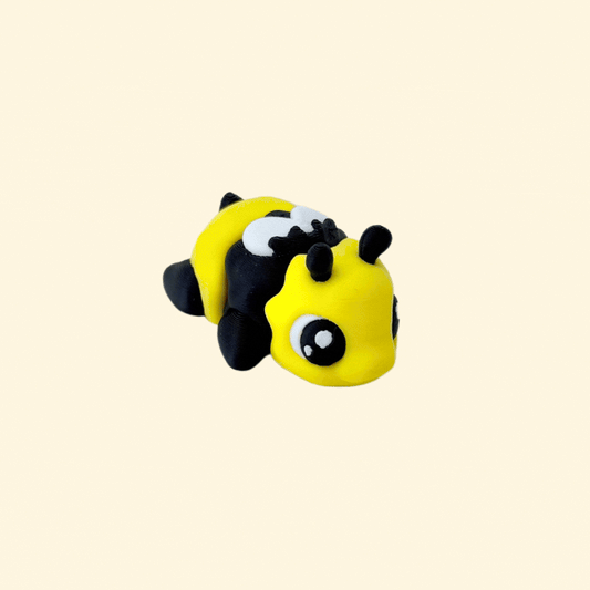A friendly fidget bee toy in black, yellow, and white, featuring cute white wings and a smiling face.