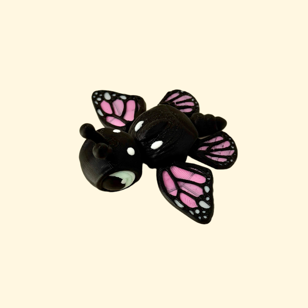 Black and pink fidget toy combining turtle and butterfly features with movable wings