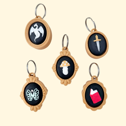 A compact cameo-style clicker fidget with a framed design and silver keyring loop.
