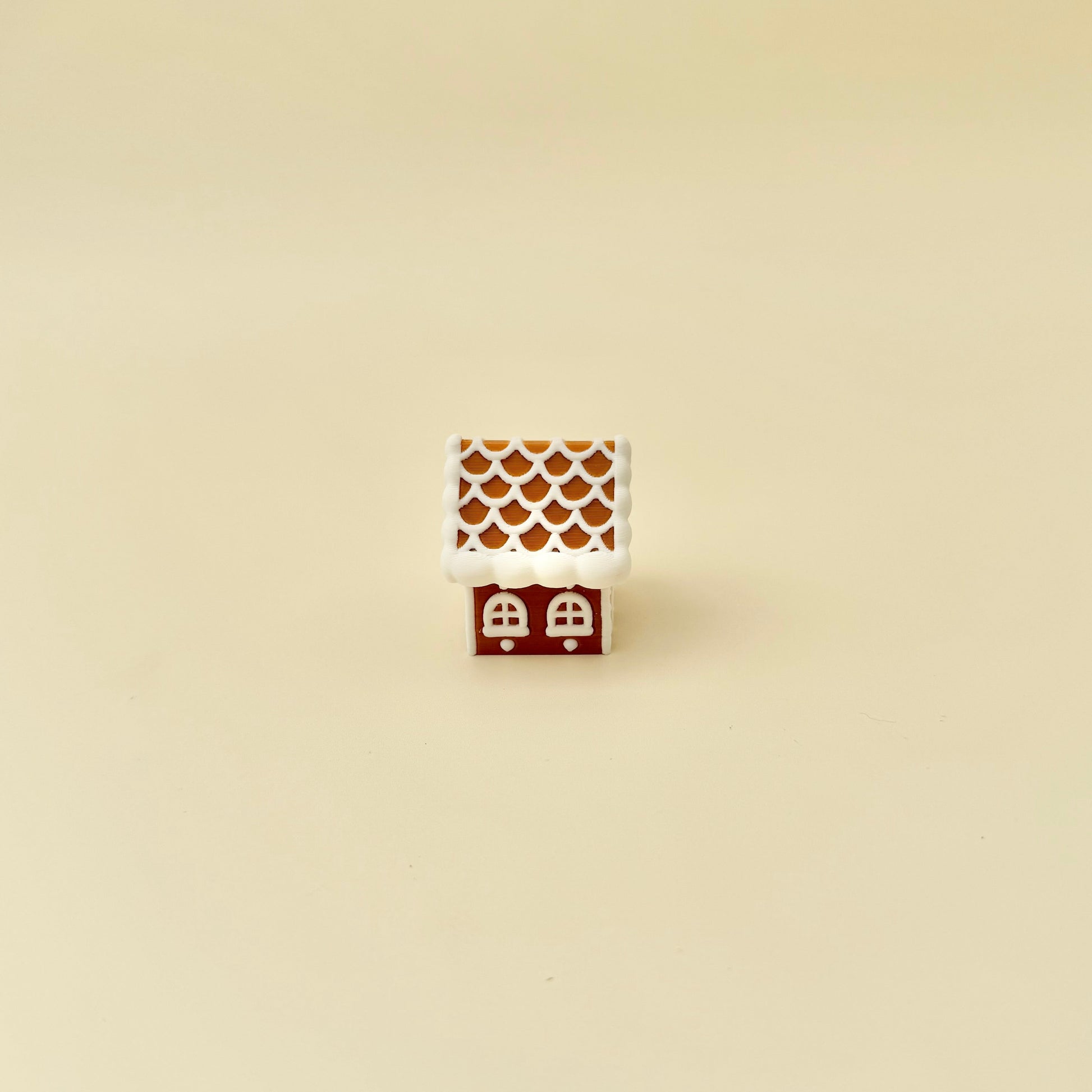 Mini gingerbread house desk toy; roof acts as the button for a satisfying click, tactile icing finish.

