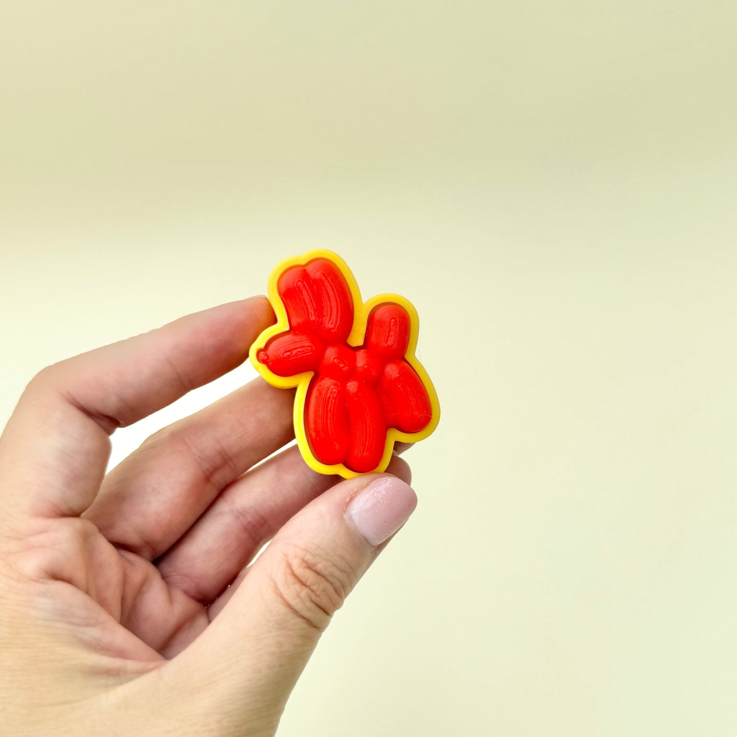 Red balloon-style dog fidget toy with a smooth, raised surface and click function.