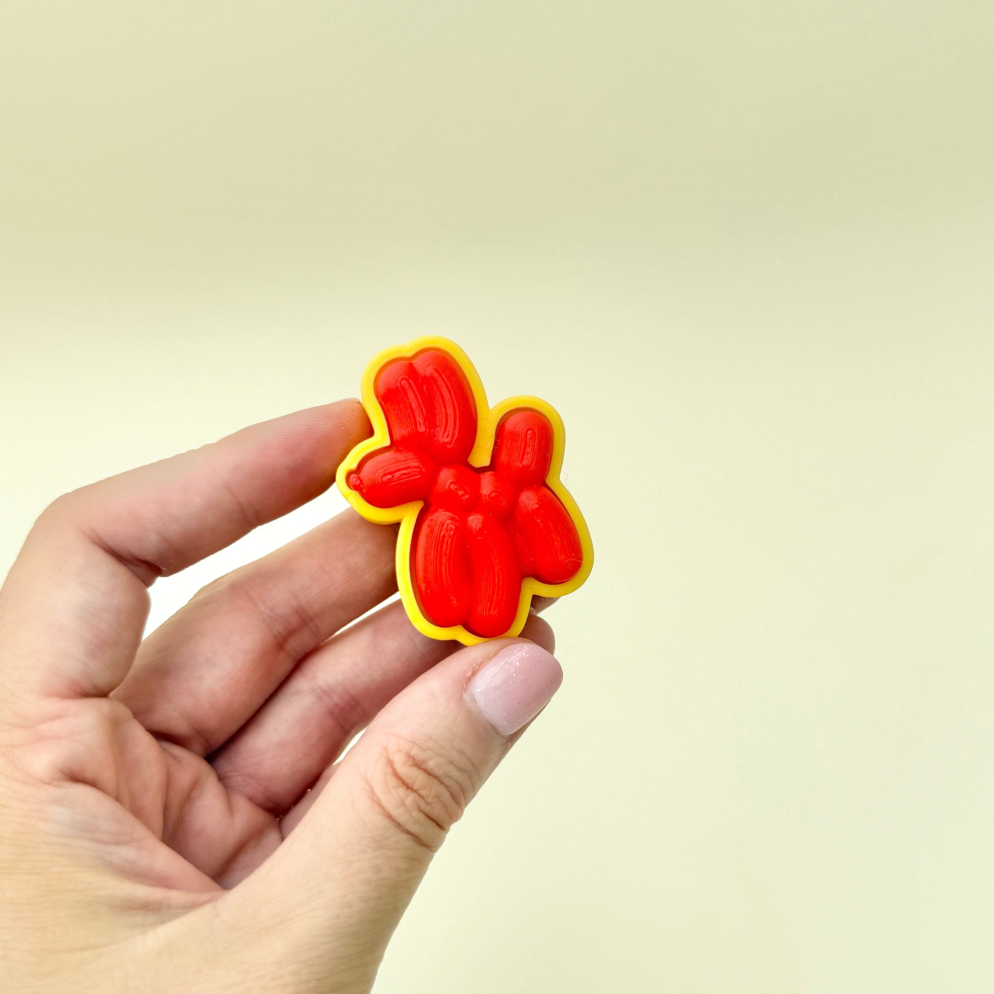 Red balloon-style dog fidget toy with a smooth, raised surface and click function.