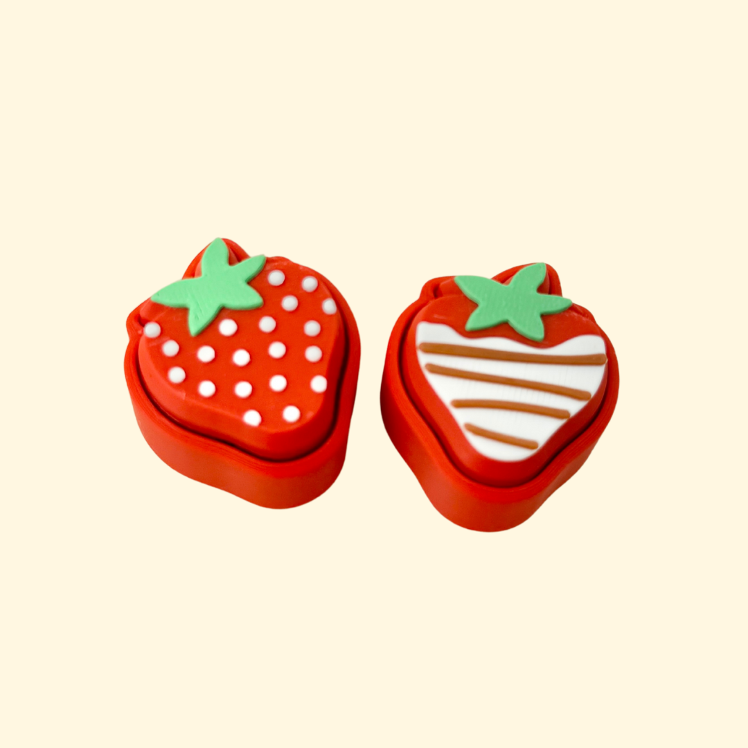 Red and brown strawberry-shaped clicker fidget with tactile texture and clicking action.
