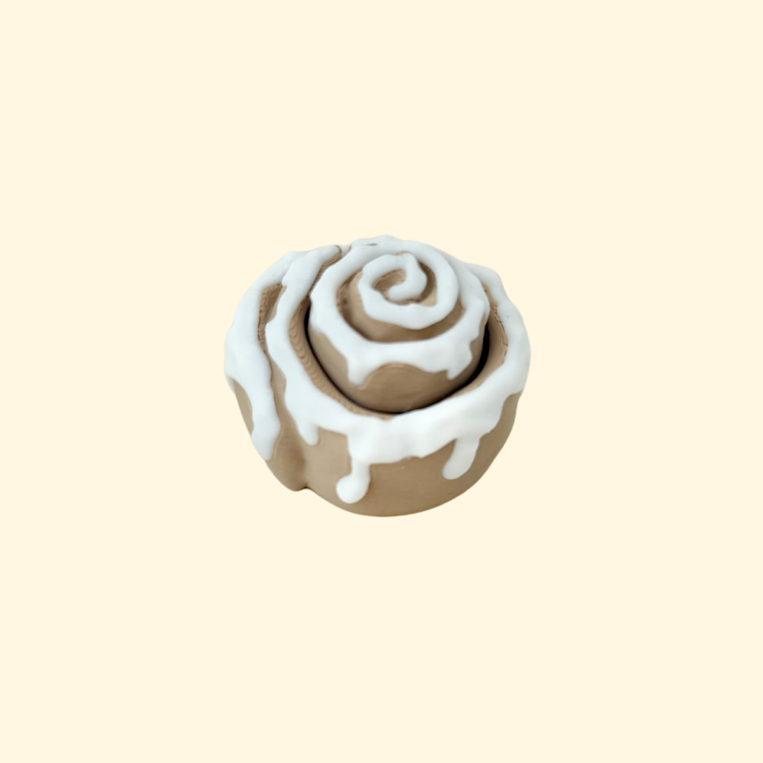 Cinnamon roll-inspired fidget clicker with swirled design and white icing.