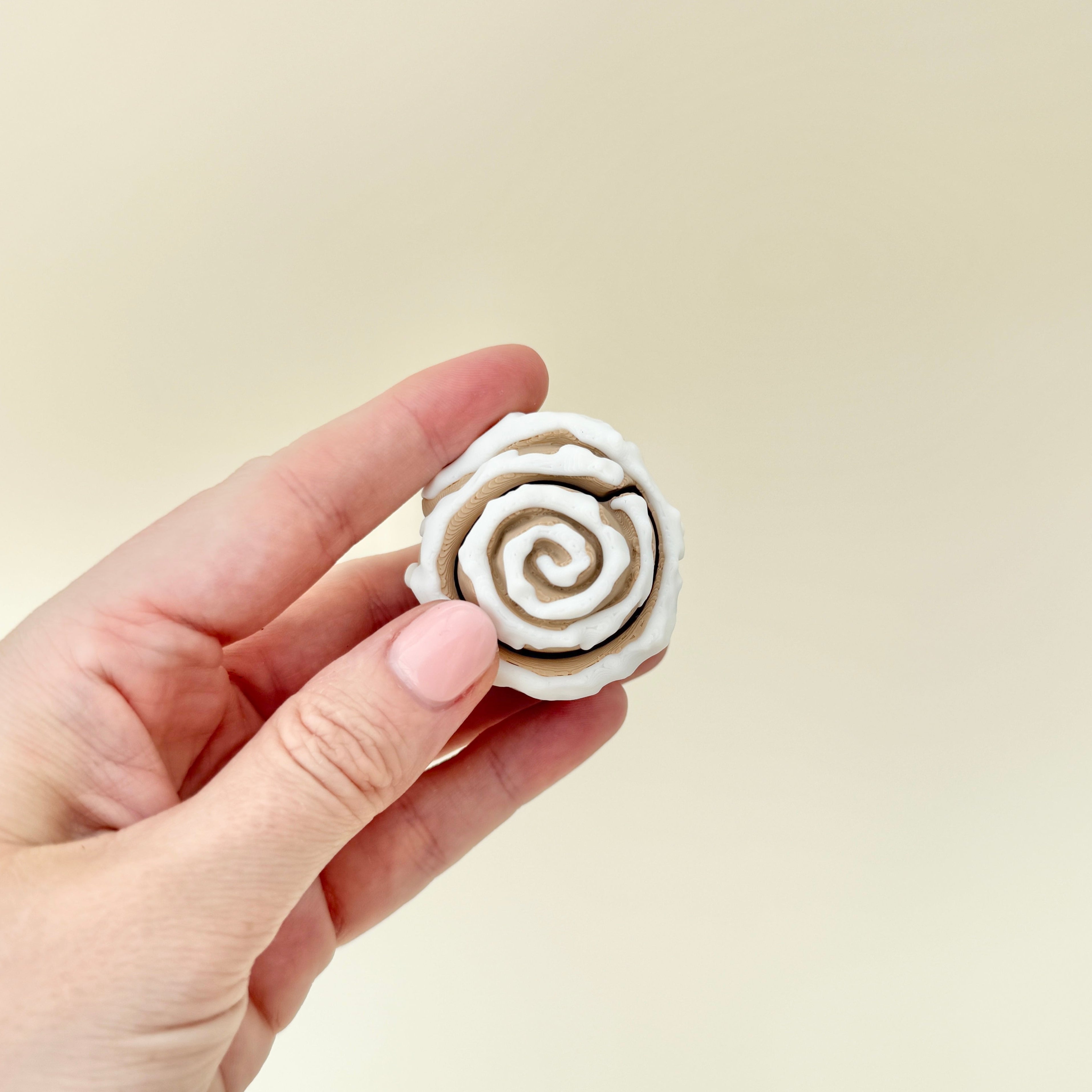 Compact cinnamon roll fidget clicker providing sensory stimulation.