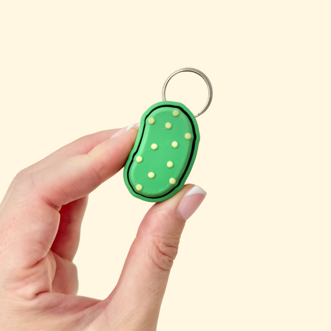 Textured pickle-shaped fidget toy with pressable top and wrist strap for tactile stimming.