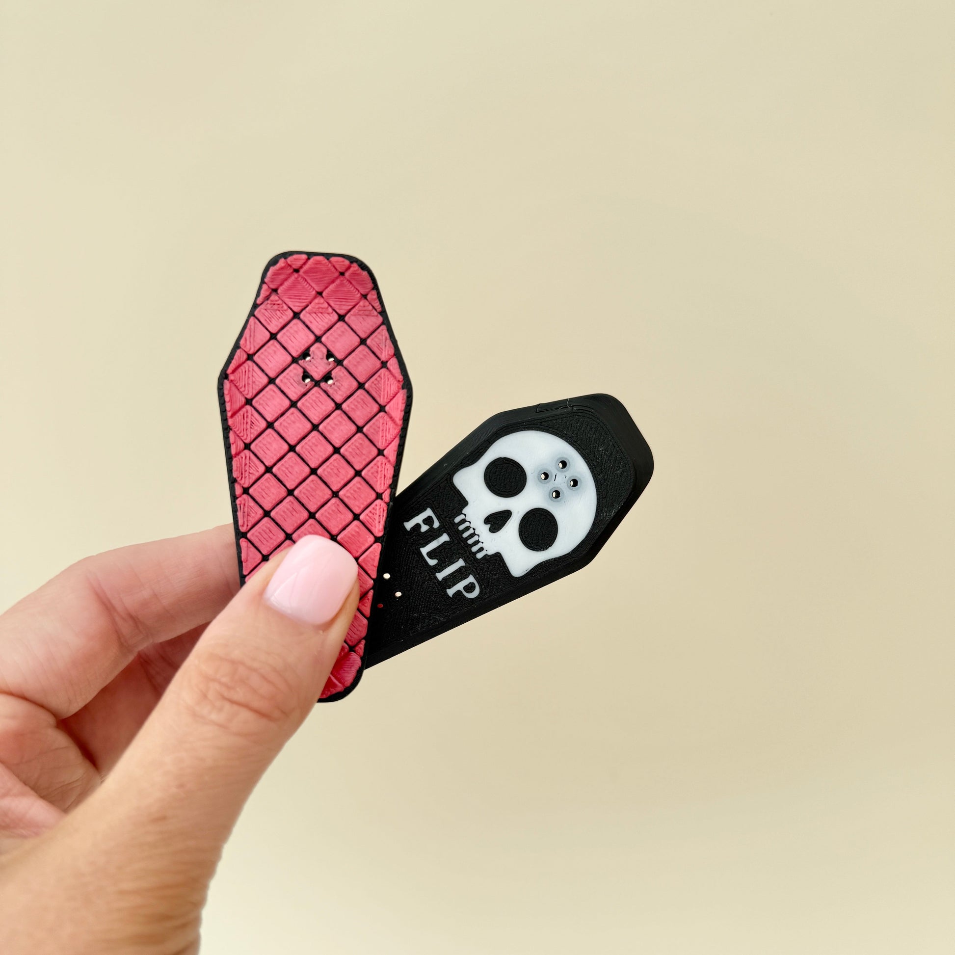 Two-piece magnet split in hand; one red textured side and one skull “flip” side.
