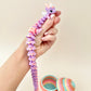 Whimsical fidget dragon with lilac and peach tones and a twinkling rainbow egg.