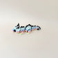 Collectable dragon fidget toy with a pastel rainbow body, white flowers, and black spiky details.