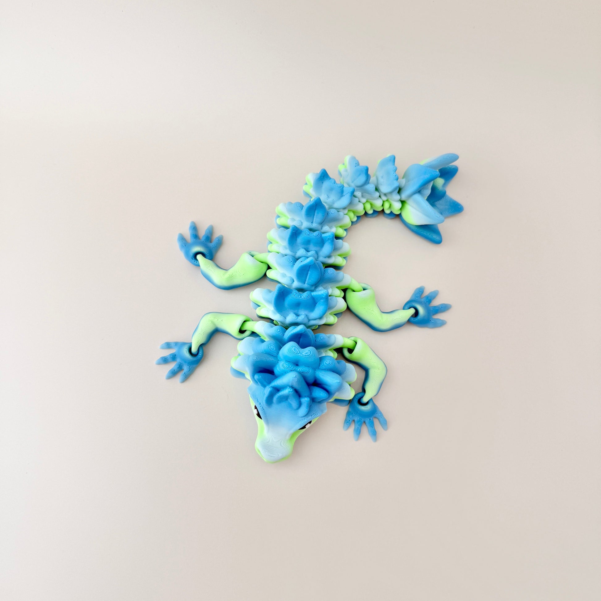 Stunning articulated dragon toy in a gradient of blue and green with realistic black and white eyes.