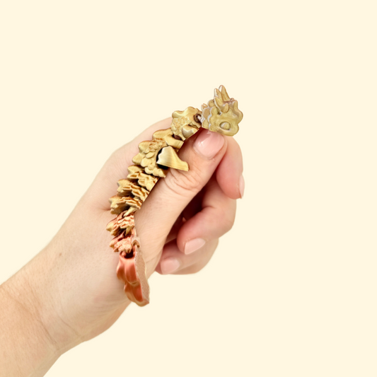 A compact fidget dragon that shifts between metallic silver, copper, and gold tones.