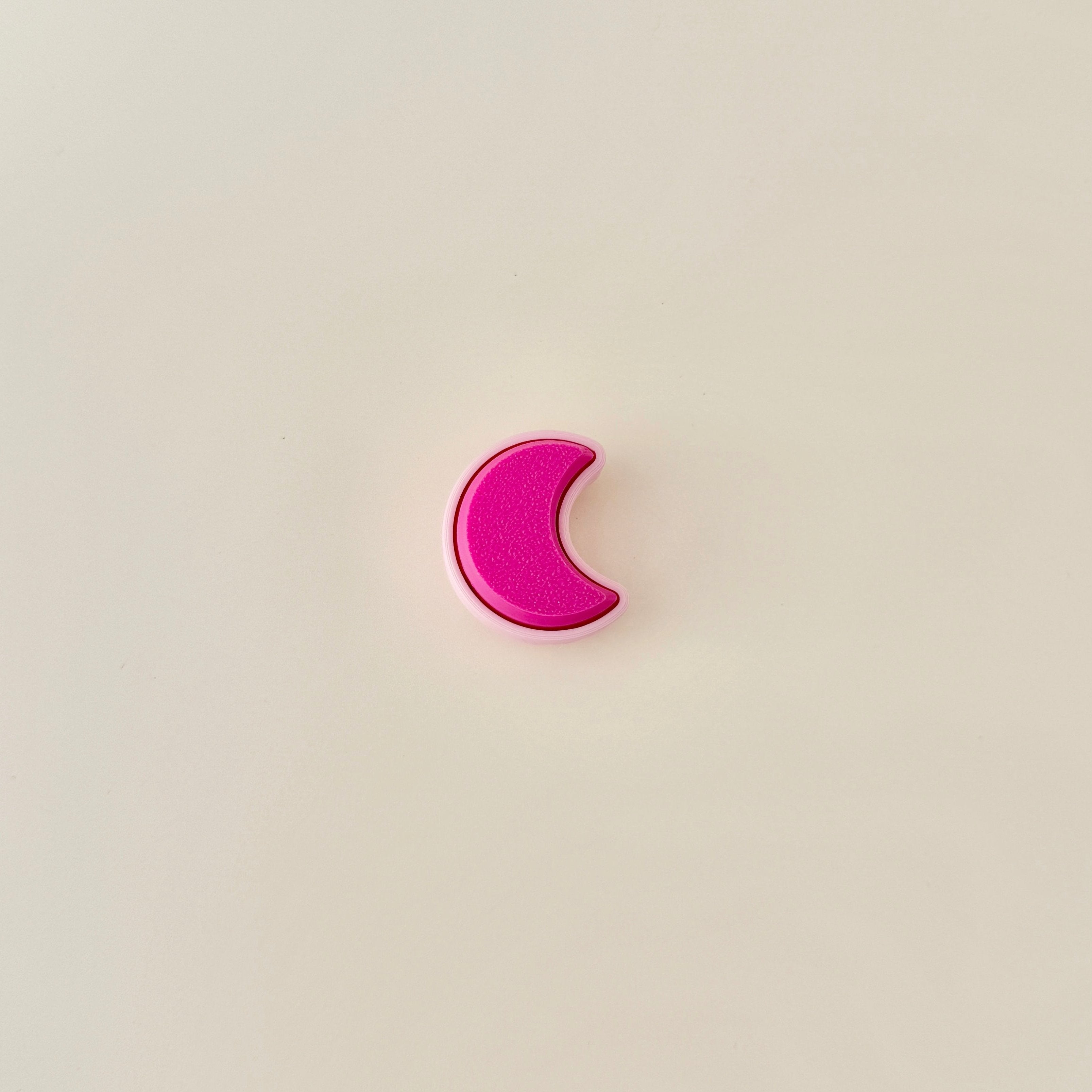 Small crescent moon fidget toy with satisfying click motion in pink hues.