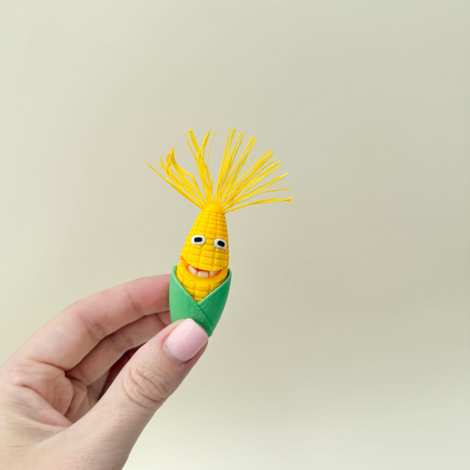 Two corn-themed fidget toys with hinged mouths and textured kernels, supplied with a small dish.
