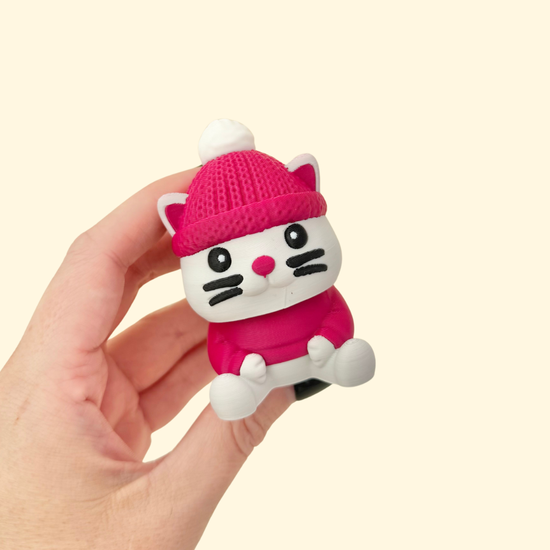 Chunky 7 cm cat-shaped fidget clicker with press-down hat and mixed smooth/knit textures.
