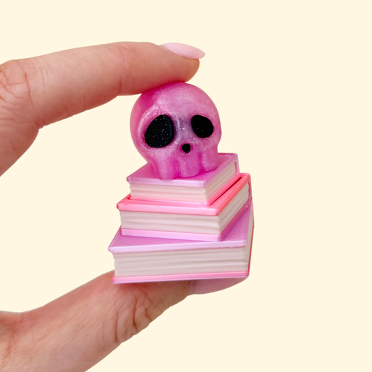 Book stack clicker fidget with glitter skull topper, tactile sensory toy for focus and grounding.
