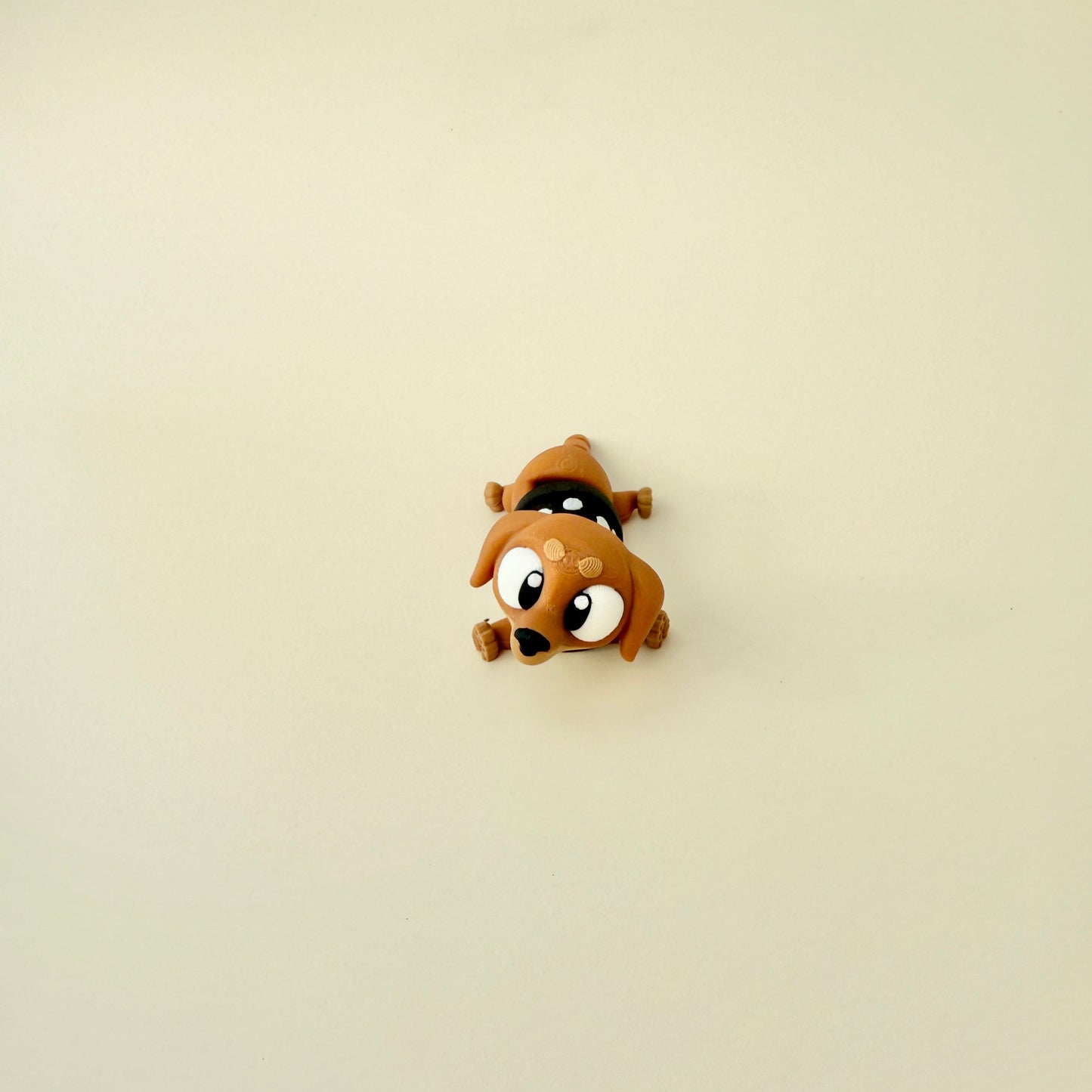 A close-up of the sausage dog fidget toy, showing its fully articulated legs, wagging tail, and adorable black-and-white spotted jumper.
