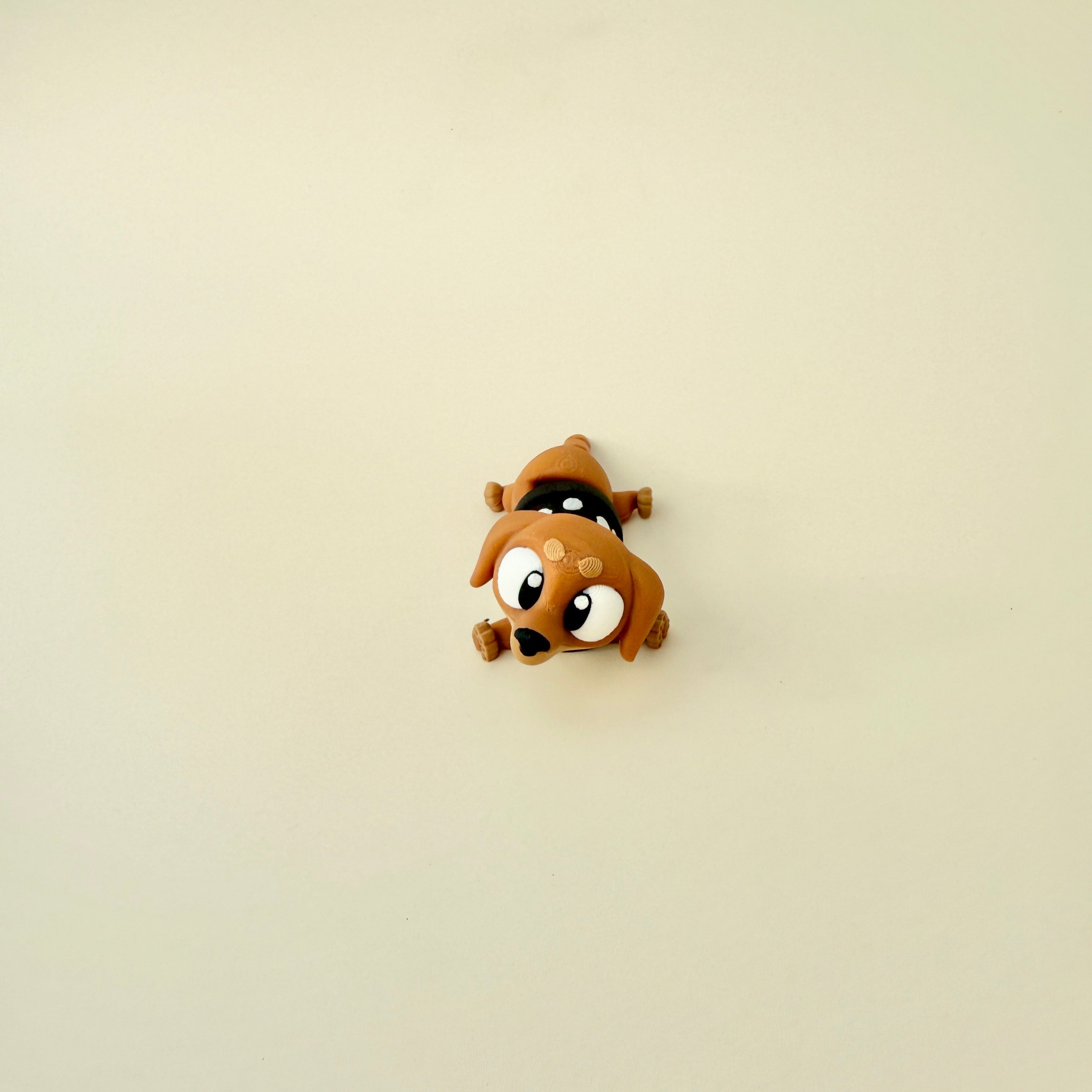 A close-up of the sausage dog fidget toy, showing its fully articulated legs, wagging tail, and adorable black-and-white spotted jumper.