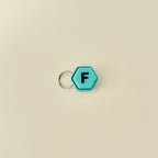 A compact hexagonal fidget toy that clicks when pressed, available with all 26 letters of the alphabet.